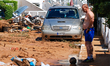 A man watching the street in front of his house filled with mud and derbis the day after f...