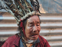 A 90 year-old Lepcha Bomthing (Lepcha priest) wearing a feathered hat chants prayers and cries for the dead villagers during an animal sacri...