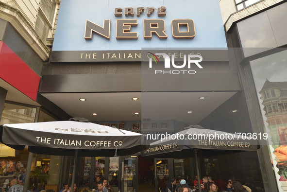 Light shining on to the Cafe Nero sign as people sit underneath parasols on Monday 11th May 2015 in Manchester. 