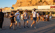 Locals and tourists are seen with facemask walking at the waterfront promenade of the old...