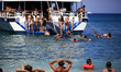 Tourists enjoy a summer evening at Xigia beach as a boat with other tourists approaches in...