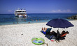 Tourists enjoy a summer evening at Xigia beach as a boat with other tourists approaches in...