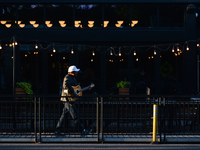A man playing a guitar walks past empty tables outside a restaurant on Whyte Avenue in Edmonton center.
Alberta has declared a state of publ...