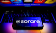 Sorare logo displayed on a phone screen and Sorare website displayed on a laptop screen ar...