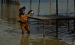 An indian boy,dressed as hindu God Shiva,crosses the road,filled with water of floooded Ga...