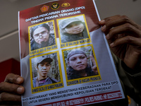 A police officer shows photos of the remaining four members of the Poso East Indonesia Mujahidin (MIT) Terrorist Search List (DPO) at the Ce...