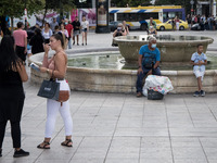 People are sitted at a fountain at Syntagma square in the center of Athens, Greece on September 22, 2021. (