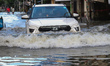 Commuters wade through a water logged street because of heavy rain and Coronavirus pandemi...