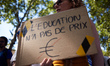 A woman holds a cardboard reading 'Education has no price'. Teachers on strike protested i...