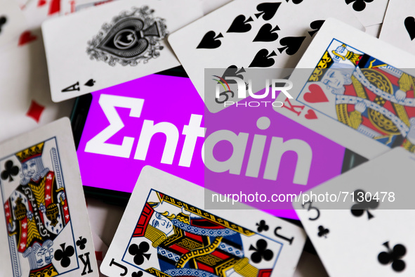 Entain logo displayed on a phone screen is seen with playing cards in this illustration photo taken in Krakow, Poland on September 25, 2021....