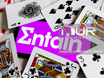 Entain logo displayed on a phone screen is seen with playing cards in this illustration photo taken in Krakow, Poland on September 25, 2021....