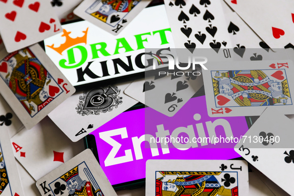 Entain and DraftKings logos displayed on phone screens are seen with playing cards in this illustration photo taken in Krakow, Poland on Sep...