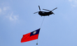 A Chinook Helicopter carrying the biggest  Taiwan flag ever flies over a military camp, as...