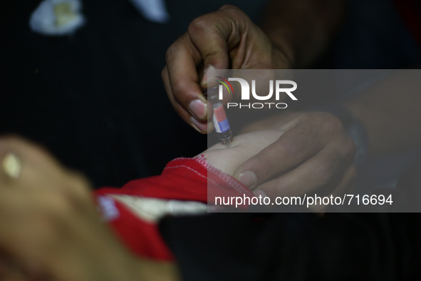 A nurse gives Measles Mumps Rubella (MMR) vaccines, to a child in the vaccine's center belongs to the Syrian Arab Red Crescent - Douma branc...