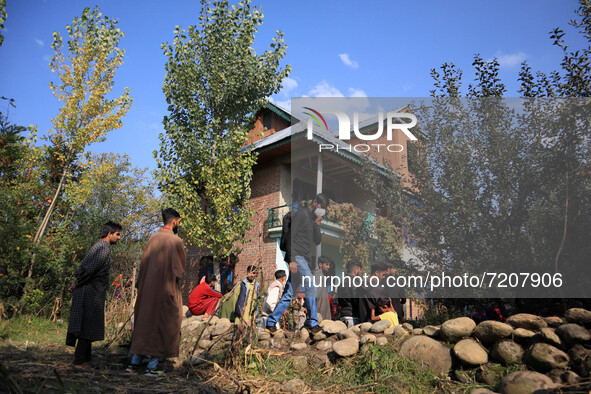 Kashmiri people stand outside a residential house where two militants were killed during an encounter between Indian forces and Kashmiri mil...