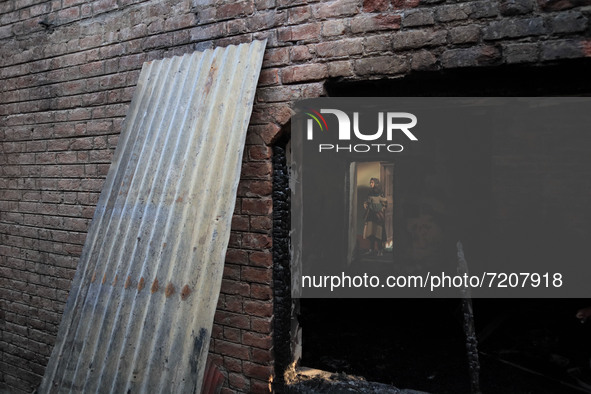 Kashmiri people assess the damaged residential house where a gunbattle took place between Indian forces and Kashmiri militants in Tulran vil...