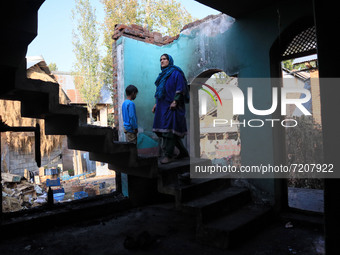 A Kashmiri woman assess her damaged residential house where a gun battle took place between Indian forces and Kashmiri militants in Tulran v...