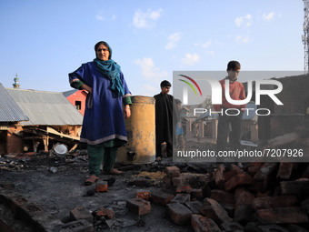 A Kashmiri woman accompanied by her children asses her damaged residential house where a gun battle took place between Indian forces and Kas...