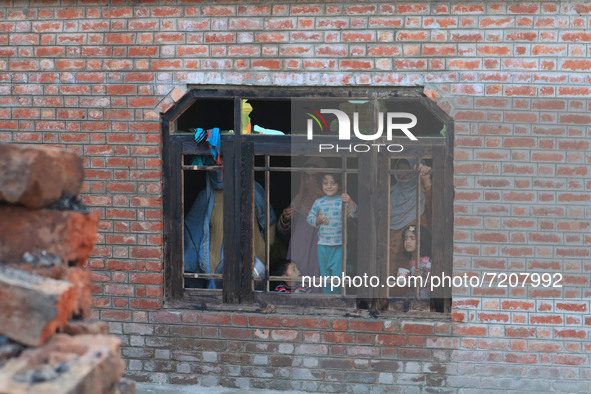 Kashmiri people look out of a damaged residential house where a gun battle took place between Indian forces and Kashmiri militants in Tulran...
