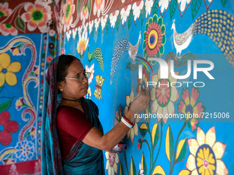 A woman draws traditional motifs on a wall of her house at Tikoil village in Nachole upazila of Chapainawabganj district of Bangladesh. (
