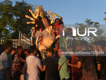 Hindu devotees prepare immerse a clay idol of the Hindu Goddess Durga in a river on the last day of Durga Puja Festival, on October 15, 2021...