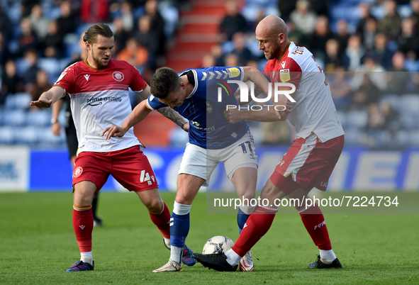Oldham Athletic's Zak Dearnley tussles with Jake Reeves of Stevenage Football Club and Scott Cuthbert of Stevenage Football Club during the...