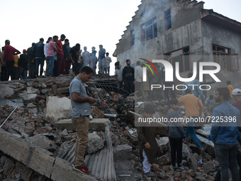 Kashmiri people assess the damaged residential houses  near the gun battle site in Pampore area of Pulwama district south of Srinagar, India...