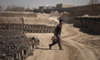An Afghan refugee labor carries newly bricks to pile up after removing them from a kiln in...