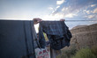 An Afghan refugee labor hangs his washed clothes from a rope out of his hut which is share...