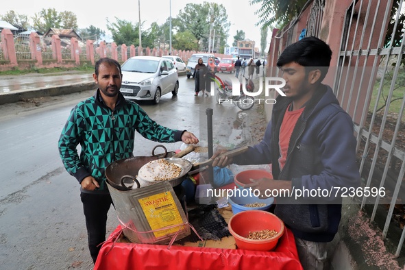 A Kashmiri man purchases snacks from Rishik, 21, a Non-Local worker outside a Shrine in Sopore, District Baramulla, Jammu and Kashmir, India...