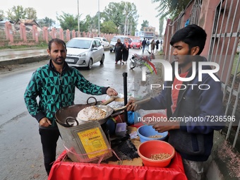 A Kashmiri man purchases snacks from Rishik, 21, a Non-Local worker outside a Shrine in Sopore, District Baramulla, Jammu and Kashmir, India...