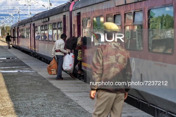 Indian migrant workers wait with their belongings board a train to their home states following attacks on migrant labourers by unknown Gunme...