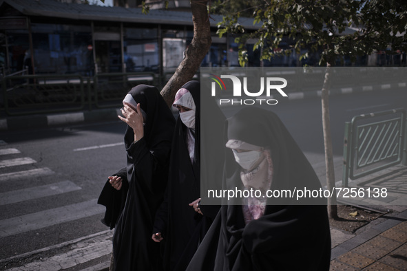 Iranian veiled women wearing protective face masks walk along an avenue to the University of Tehran for taking part the Friday prayers cerem...