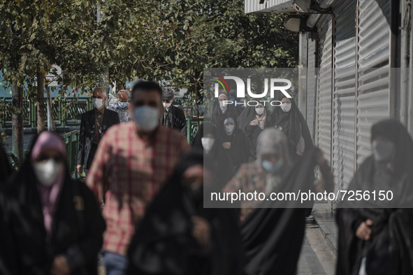 Iranian people wearing protective face masks walk along an avenue to the University of Tehran for taking part the Friday prayers ceremonies...
