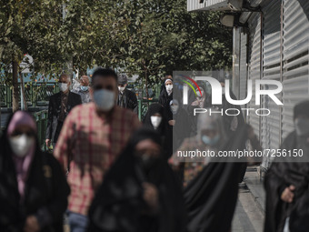 Iranian people wearing protective face masks walk along an avenue to the University of Tehran for taking part the Friday prayers ceremonies...