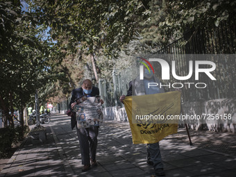 An Iranian elderly man wearing a protective face mask carrying an anti-U.S. flag while walking along an avenue to the University of Tehran f...