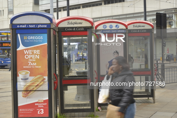 Payphones standing idle as a person walks by speaking on their mobile phone on Tuesday 5th May 2015. 