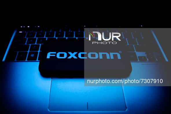 Foxconn logo displayed on a phone screen and a laptop keyboard are seen in this illustration photo taken in Krakow, Poland on October 30, 20...