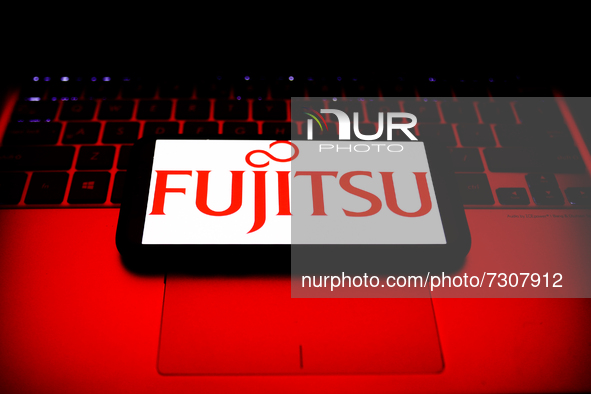 Fujitsu logo displayed on a phone screen and a laptop keyboard are seen in this illustration photo taken in Krakow, Poland on October 30, 20...