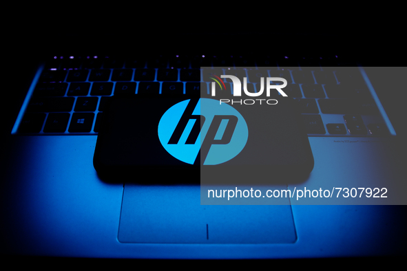 HP logo displayed on a phone screen and a laptop keyboard are seen in this illustration photo taken in Krakow, Poland on October 30, 2021. 