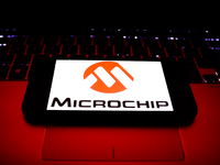 Microchip logo displayed on a phone screen and a laptop keyboard are seen in this illustration photo taken in Krakow, Poland on October 30,...