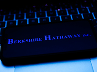 Berkshire Hathaway logo displayed on a phone screen and a laptop keyboard are seen in this illustration photo taken in Krakow, Poland on Oct...