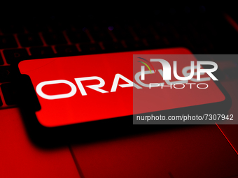 Oracle logo displayed on a phone screen and a laptop keyboard are seen in this illustration photo taken in Krakow, Poland on October 30, 202...