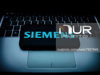 Siemens logo displayed on a phone screen and a laptop keyboard are seen in this illustration photo taken in Krakow, Poland on October 30, 20...