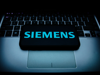 Siemens logo displayed on a phone screen and a laptop keyboard are seen in this illustration photo taken in Krakow, Poland on October 30, 20...