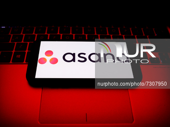 Asana logo displayed on a phone screen and a laptop keyboard are seen in this illustration photo taken in Krakow, Poland on October 30, 2021...