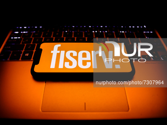Fiserv logo displayed on a phone screen and a laptop keyboard are seen in this illustration photo taken in Krakow, Poland on October 30, 202...