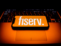 Fiserv logo displayed on a phone screen and a laptop keyboard are seen in this illustration photo taken in Krakow, Poland on October 30, 202...