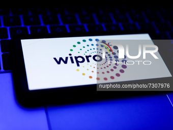 Wipro logo displayed on a phone screen and a laptop keyboard are seen in this illustration photo taken in Krakow, Poland on October 31, 2021...