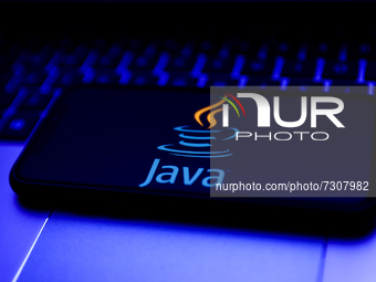 Java logo displayed on a phone screen and a laptop keyboard are seen in this illustration photo taken in Krakow, Poland on October 31, 2021....